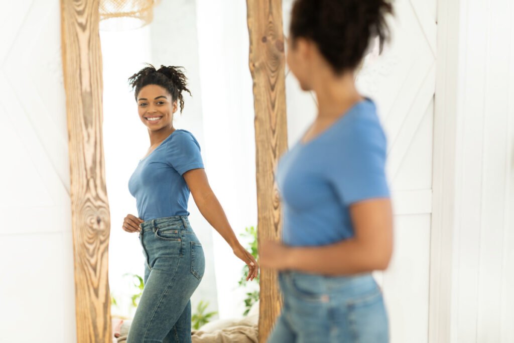 Woman Looks in Mirror Considering Tummy Tuck or Body Lift