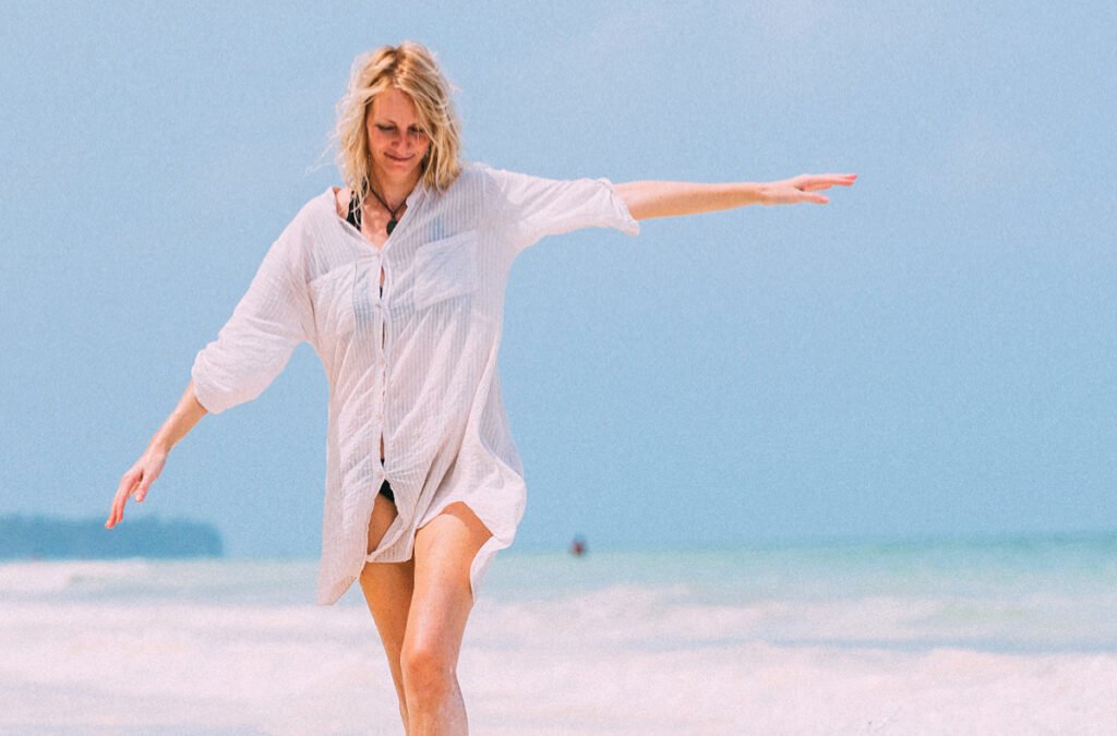 Mature Woman Raised Arms Walking Along the Beach