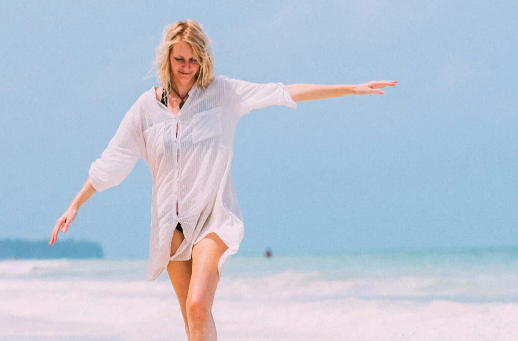 Mature Woman Raised Arms Walking Along the Beach