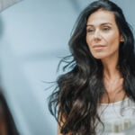 Beautiful middle aged woman looks at deep plane facelift results in the mirror