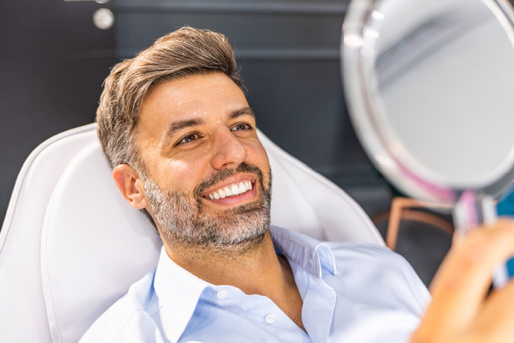 Man smiling in mirror after injectables treatment at a med spa