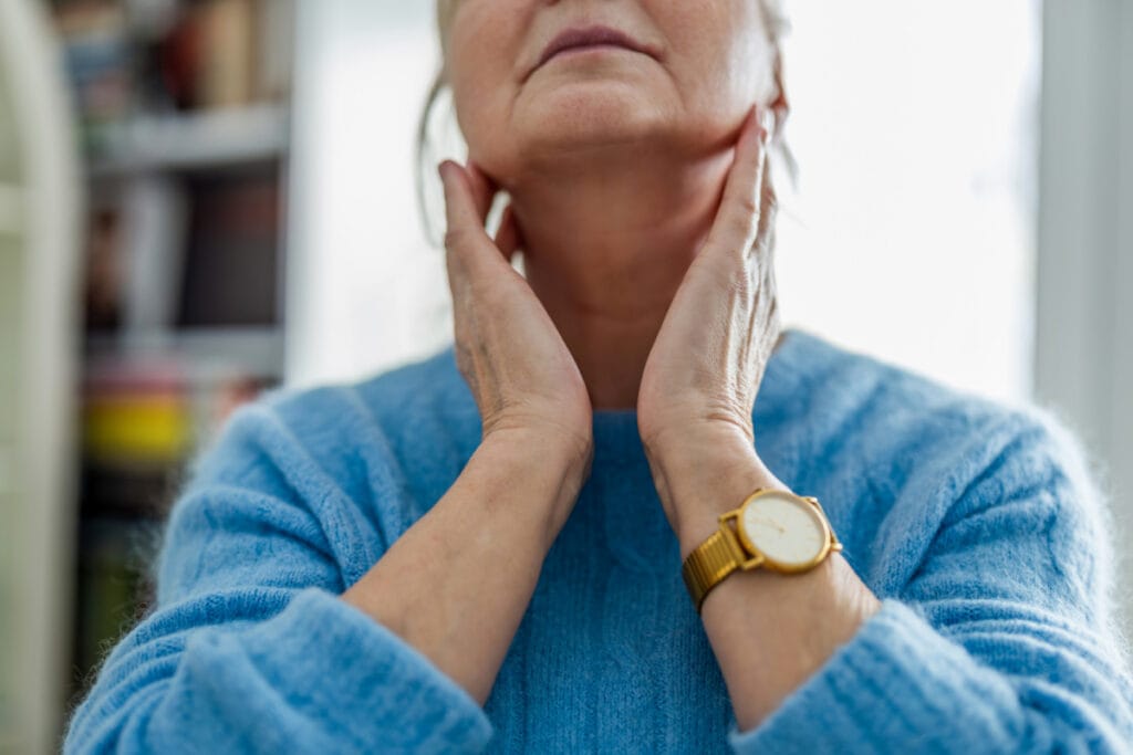 Mature woman touching rejuvenated neck after neck rejuvenation and skin tightening treatments